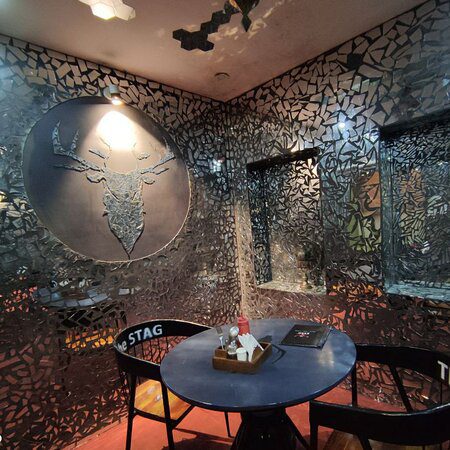 The Stag Rooftop Restro Cafe in Jaipur with a stunning night view of Amer Fort and blue, cozy rooftop seating.