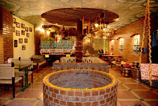 Sunlight streaming into the interior of a Jaipur building, illuminating the warm pink or traditional fresco-painted walls and a vaulted ceiling.