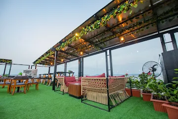 Upscale rooftop restaurant in Jaipur with open-air candlelit tables, modern black and white decor, and glass railings offering a panoramic view of the C Scheme area.