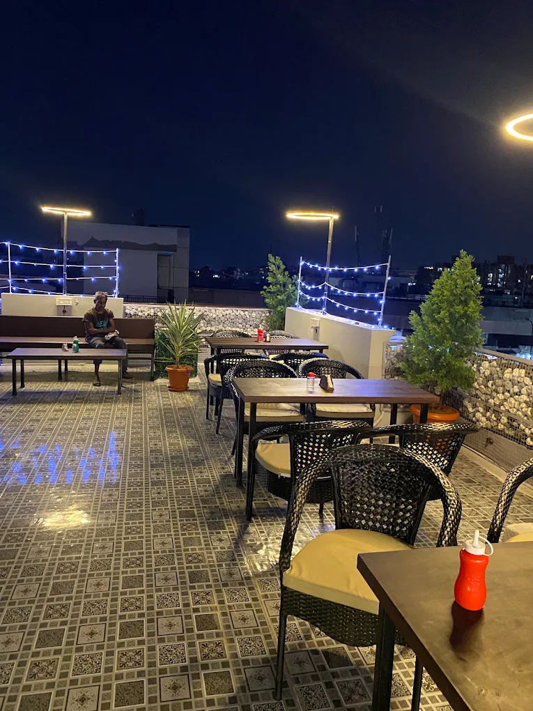 "D' Oasis Cafe Jaipur rooftop seating area with open night view"