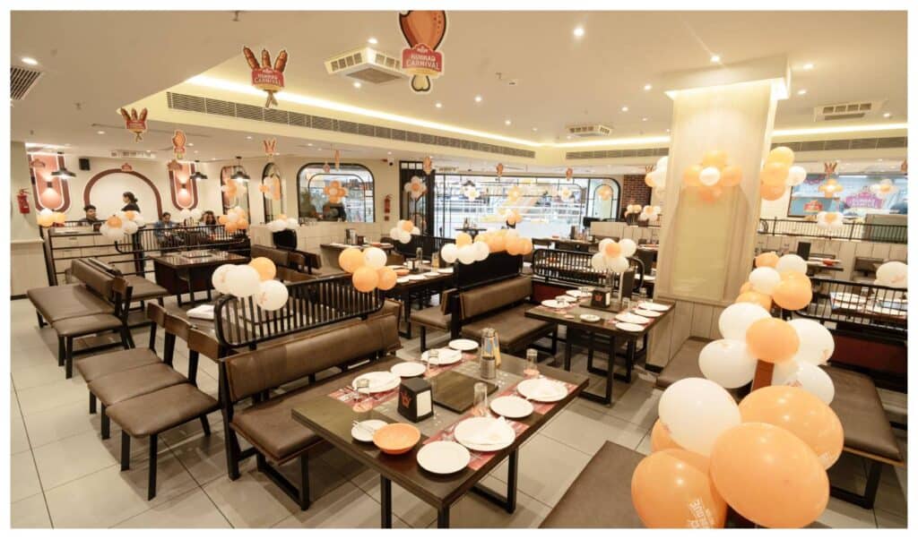 A family of four smiling while enjoying an interactive meal around the table grill at a Barbeque Nation restaurant.